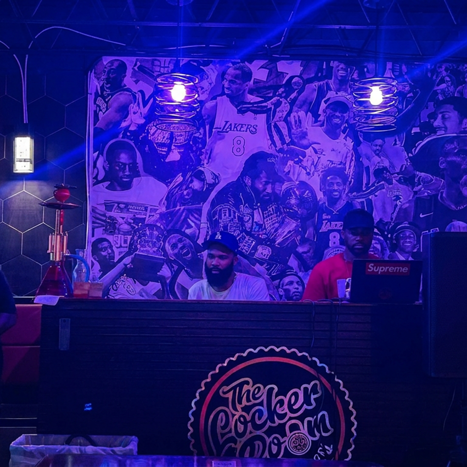 Purple-lit sports bar with a DJ booth, Lakers basketball mural, glowing number eight, and two men behind the counter.